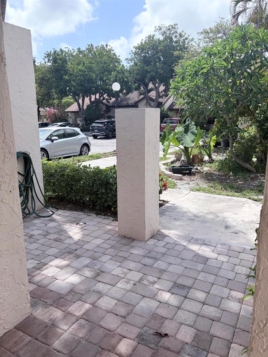 A paved patio area features a central stucco pillar and a view of a parking lot — 3072 Inglewood Terrace, Boca Raton FL 33431, BOCA RATON, FL