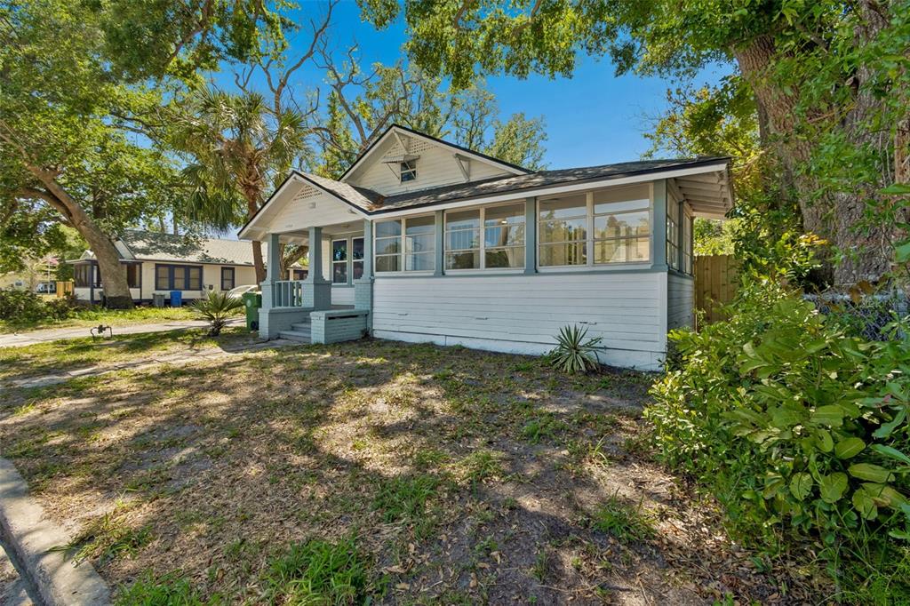 A single-story house with a white exterior, a front porch, and a large screened-in sunroom — 1002 23RD STREET W, BRADENTON, FL