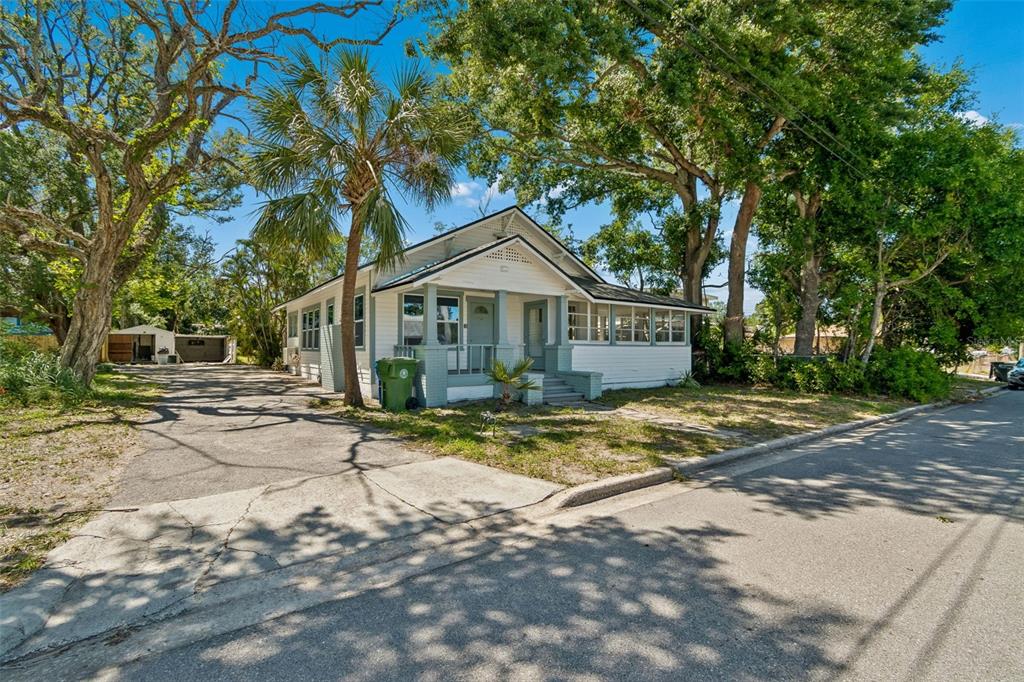 A white, single-story house with a front porch, palm tree, and driveway under large trees — 1002 23RD STREET W, BRADENTON, FL