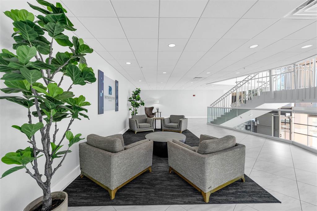 A modern office lobby features a seating area with four gray armchairs and a rug — 151 E WASHINGTON STREET UNIT 404, ORLANDO, FL