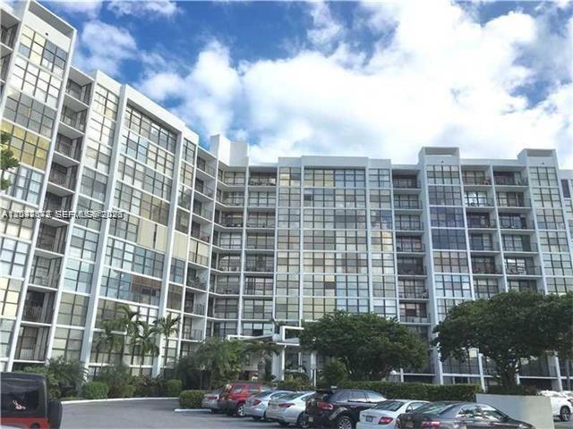 A multi-story apartment building with a glass facade stands above a parking lot — 800 Parkview Dr # 1018, Hallandale Beach FL 33009, HALLANDALE BEACH, FL