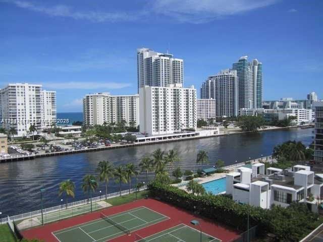 An elevated view of a tennis court, a swimming pool, a canal, and high-rise buildings — 800 Parkview Dr # 1018, Hallandale Beach FL 33009, HALLANDALE BEACH, FL