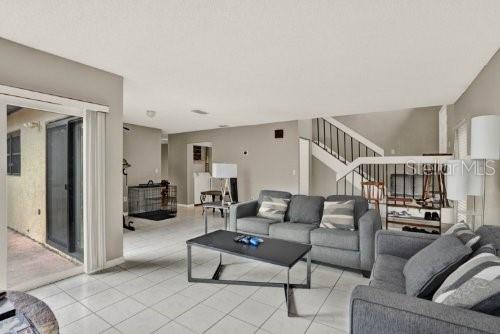 A living room features a gray sofa, a coffee table, and a staircase with railings — 451 HUNTER CIRCLE, KISSIMMEE, FL