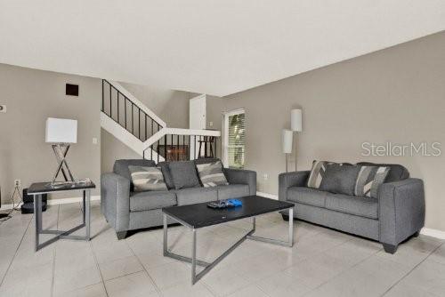 A living room features two gray sofas, a black coffee table, and a staircase — 451 HUNTER CIRCLE, KISSIMMEE, FL