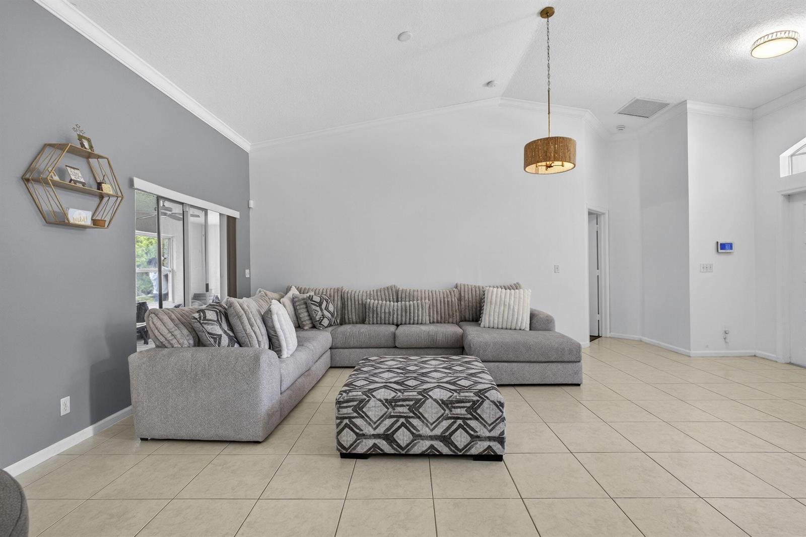 A living room features a large gray sectional sofa, a patterned ottoman, and tile flooring — 16931 N 78th Rd Road N, FL 33470, FL