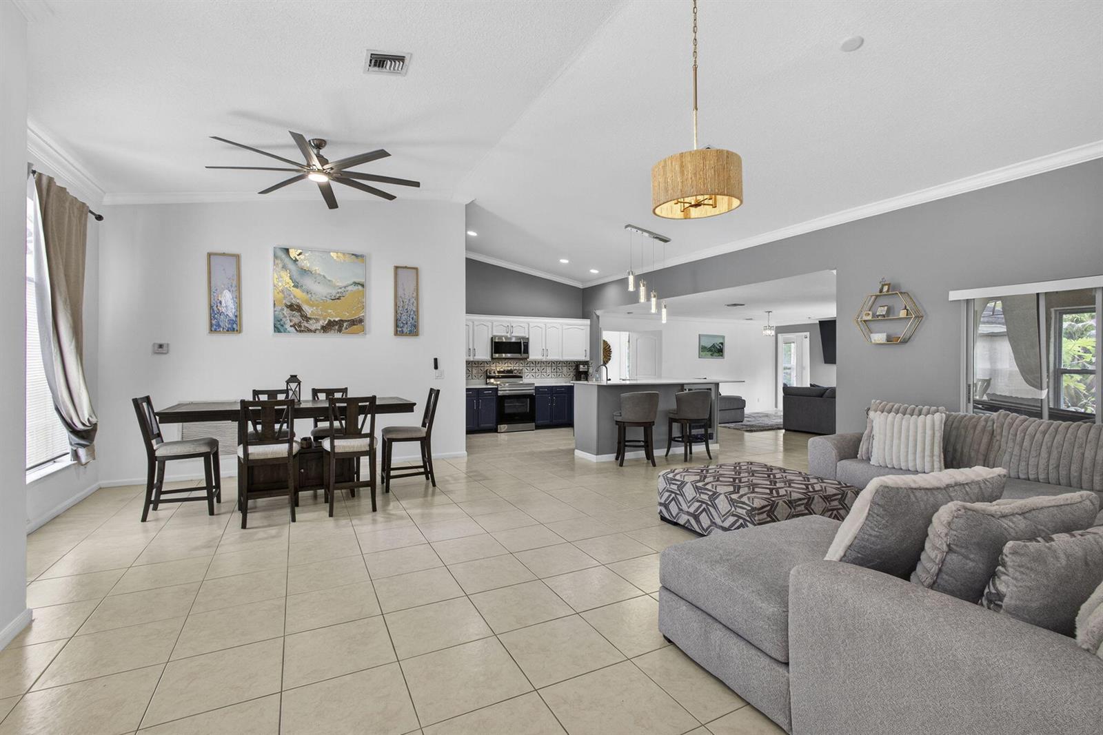 An open-concept living area features a dining space, kitchen with island, and gray sectional sofa — 16931 N 78th Rd Road N, FL 33470, FL