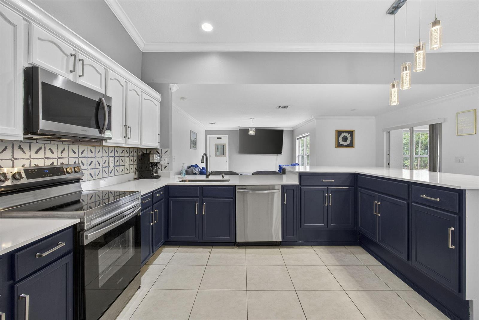 A kitchen features navy blue lower cabinets, white upper cabinets, stainless steel appliances, and tile flooring — 16931 N 78th Rd Road N, FL 33470, FL