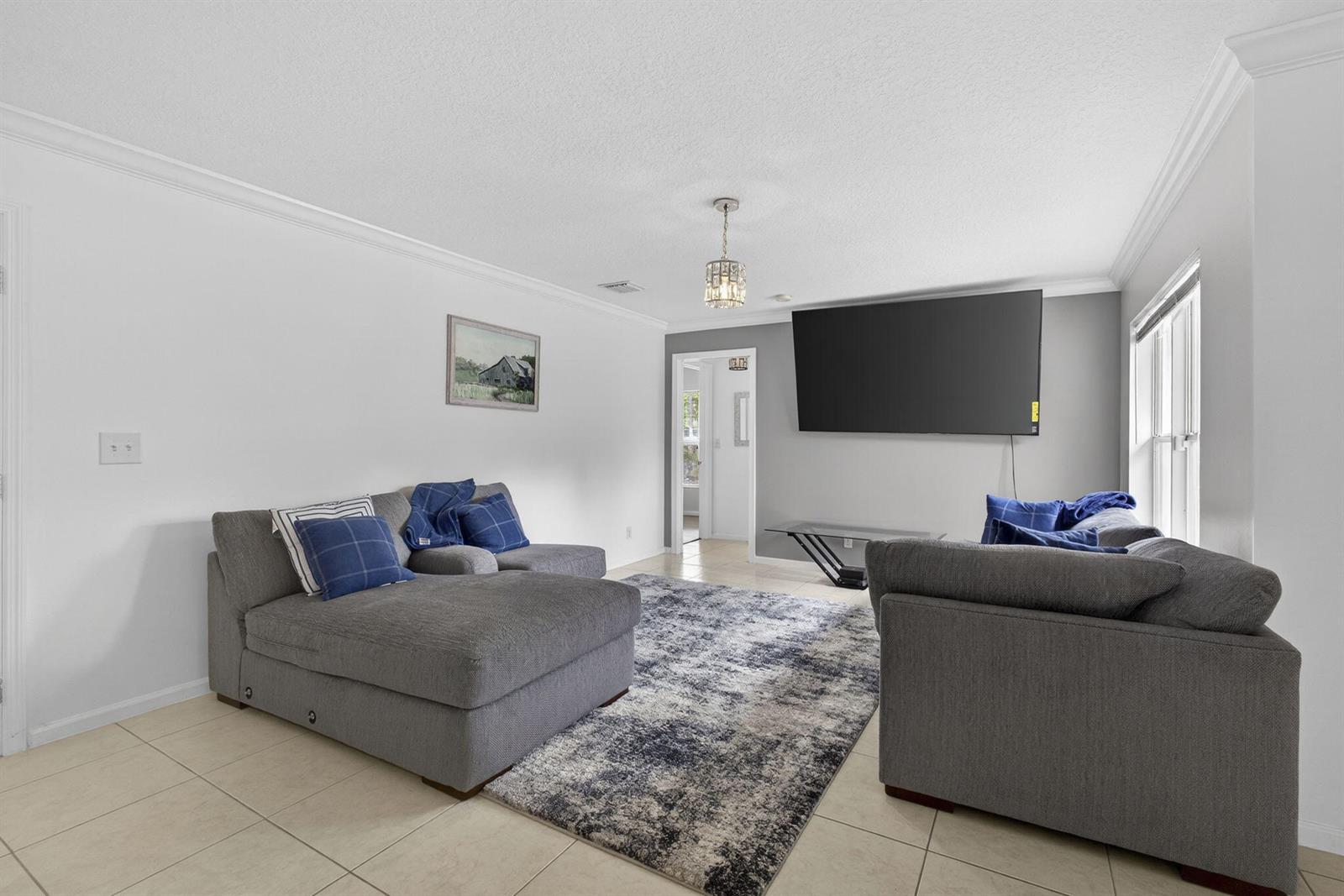 A living room features gray sofas, a patterned area rug, and a wall-mounted television — 16931 N 78th Rd Road N, FL 33470, FL