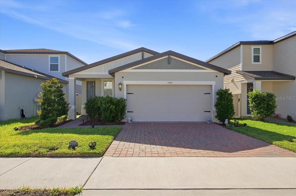 A single-story suburban house with a brick paver driveway and a two-car garage — 1912 CARNOSTIE ROAD, WINTER HAVEN, FL