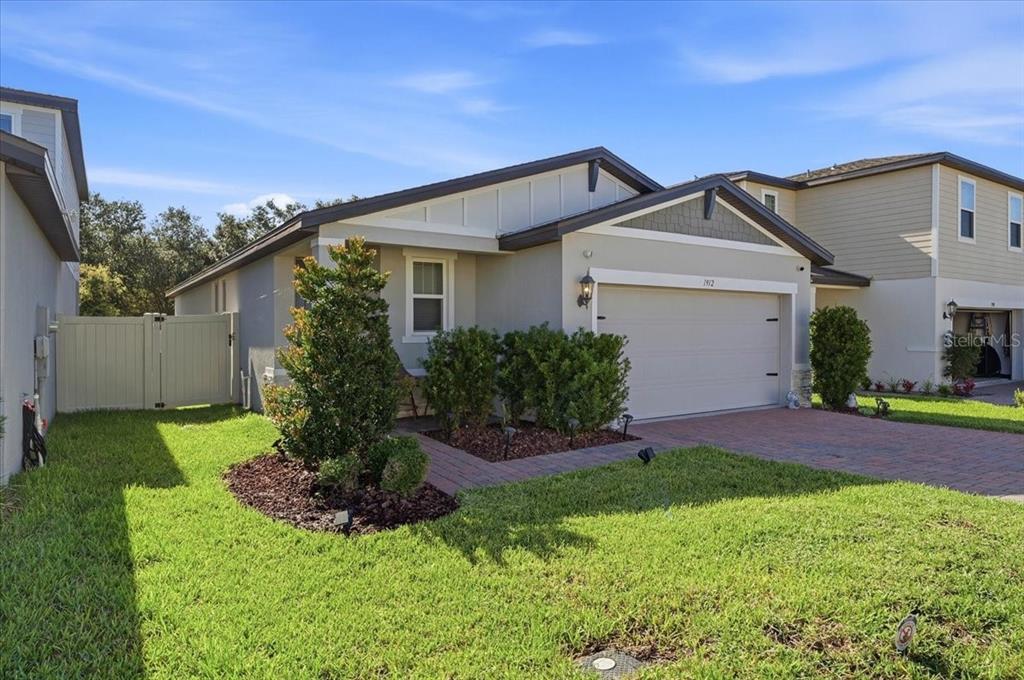 A single-story suburban house with a gray exterior, a two-car garage, and a brick walkway — 1912 CARNOSTIE ROAD, WINTER HAVEN, FL