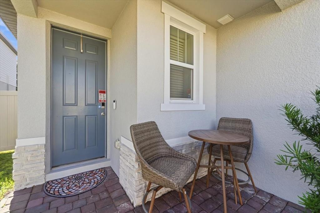 A small front porch features a blue door, a window, and a bistro table set — 1912 CARNOSTIE ROAD, WINTER HAVEN, FL