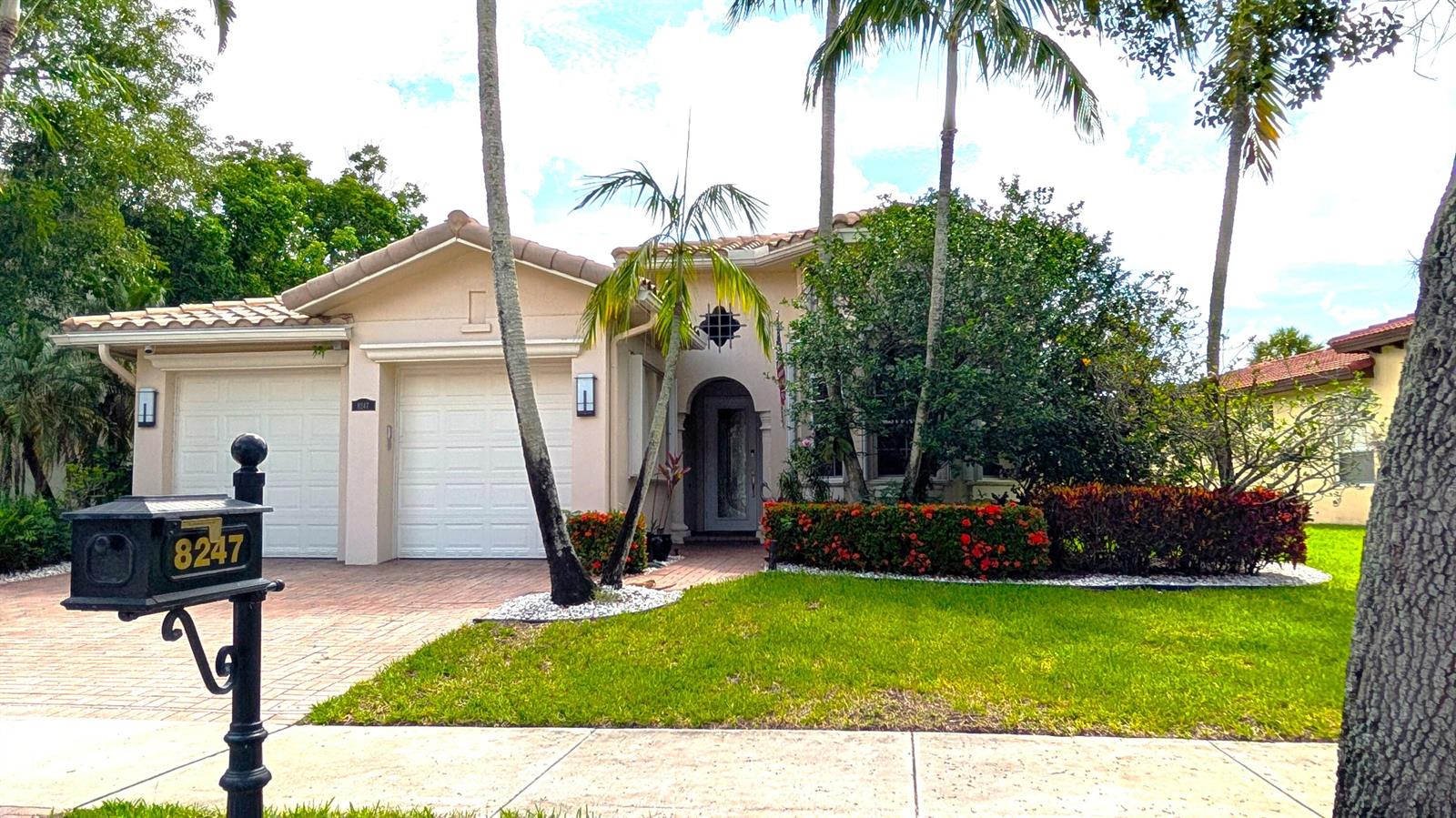 A single-story house with a two-car garage, palm trees, and a landscaped front yard — 8247 NW 107th Terrace, Parkland FL 33076, PARKLAND, FL