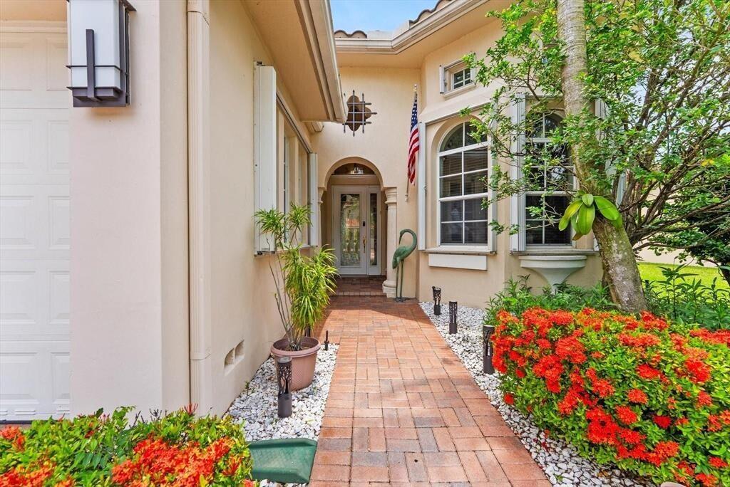 A brick walkway leads to the front entrance of a beige house with landscaping — 8247 NW 107th Terrace, Parkland FL 33076, PARKLAND, FL