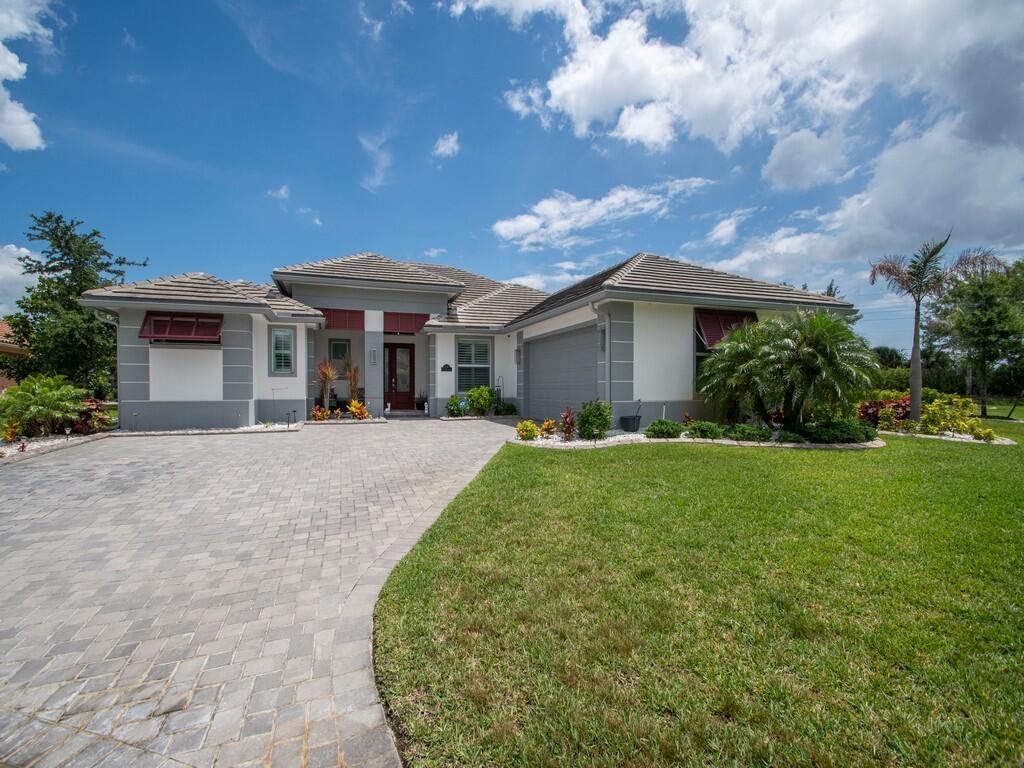 A single-story house with a gray tiled roof, white stucco walls, and a paved driveway — 8220 Halbert Lane, Vero Beach FL 32968, VERO BEACH, FL