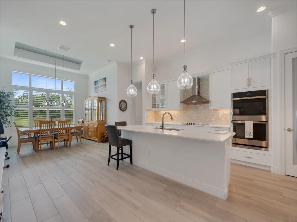 A bright kitchen features white cabinetry, a central island, and an adjacent dining area — 8220 Halbert Lane, Vero Beach FL 32968, VERO BEACH, FL