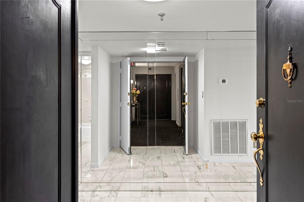 A marble-floored entryway features a mirrored wall reflecting a dark door and a bathroom — 3301 BAYSHORE BOULEVARD UNIT 509A, TAMPA, FL