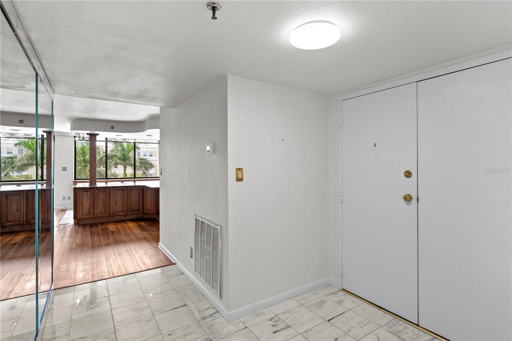 A foyer with marble flooring leads to a living area with wood floors and windows — 3301 BAYSHORE BOULEVARD UNIT 509A, TAMPA, FL