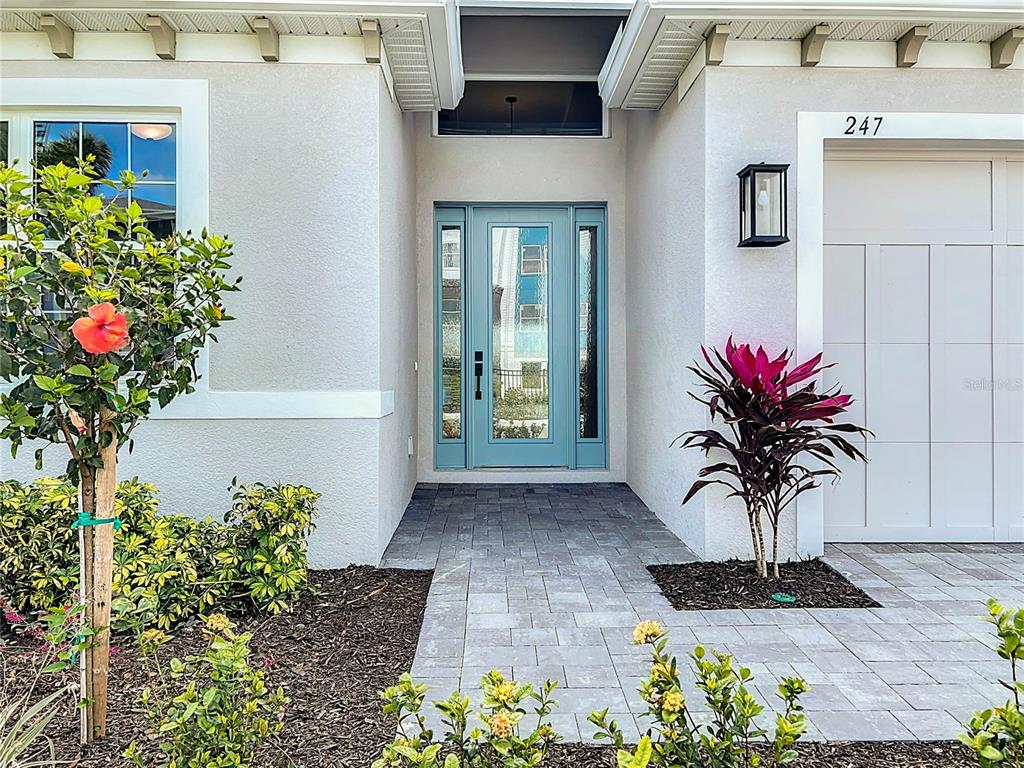 The exterior of a house features a light blue front door, stone walkway, and landscaping — 247 MONET TRAIL, BRADENTON, FL