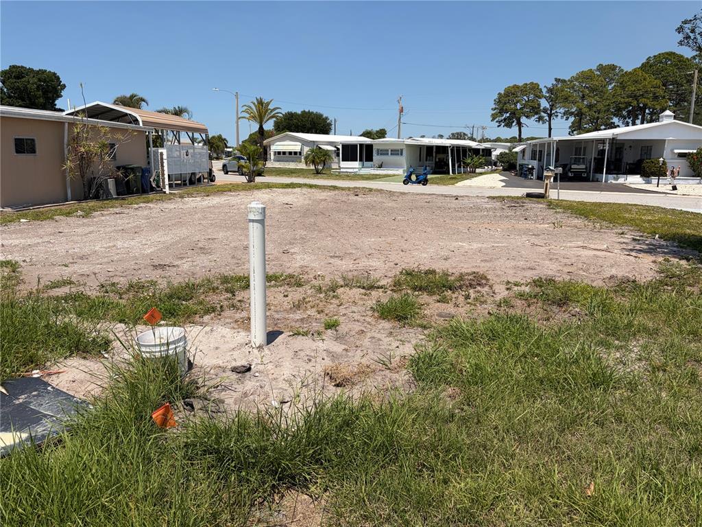 A vacant, sandy residential lot features a white utility pipe and surrounding mobile homes — 4913 OAKLAND HILLS AVENUE, SARASOTA, FL