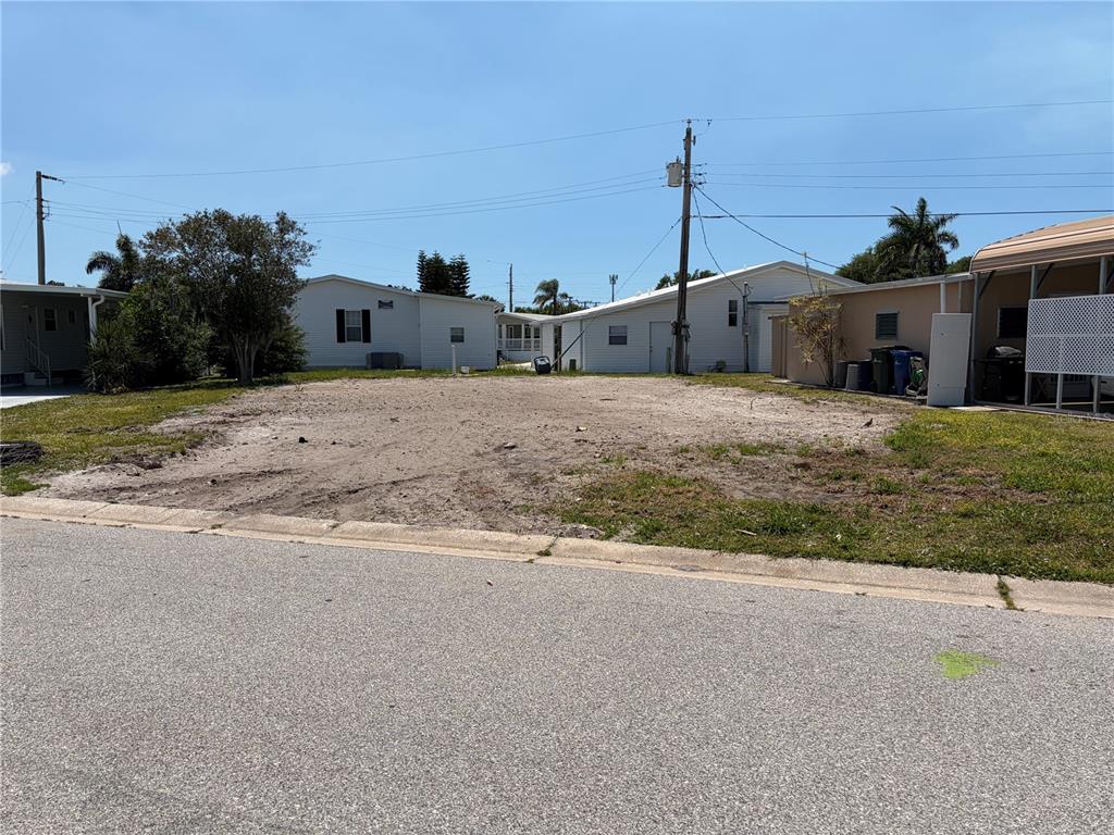 A vacant, sandy residential lot sits between two existing manufactured homes on a paved street — 4913 OAKLAND HILLS AVENUE, SARASOTA, FL