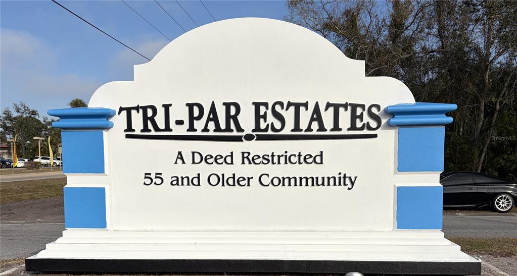 A white monument sign for Tri-Par Estates stands outdoors near a road and trees — 4913 OAKLAND HILLS AVENUE, SARASOTA, FL