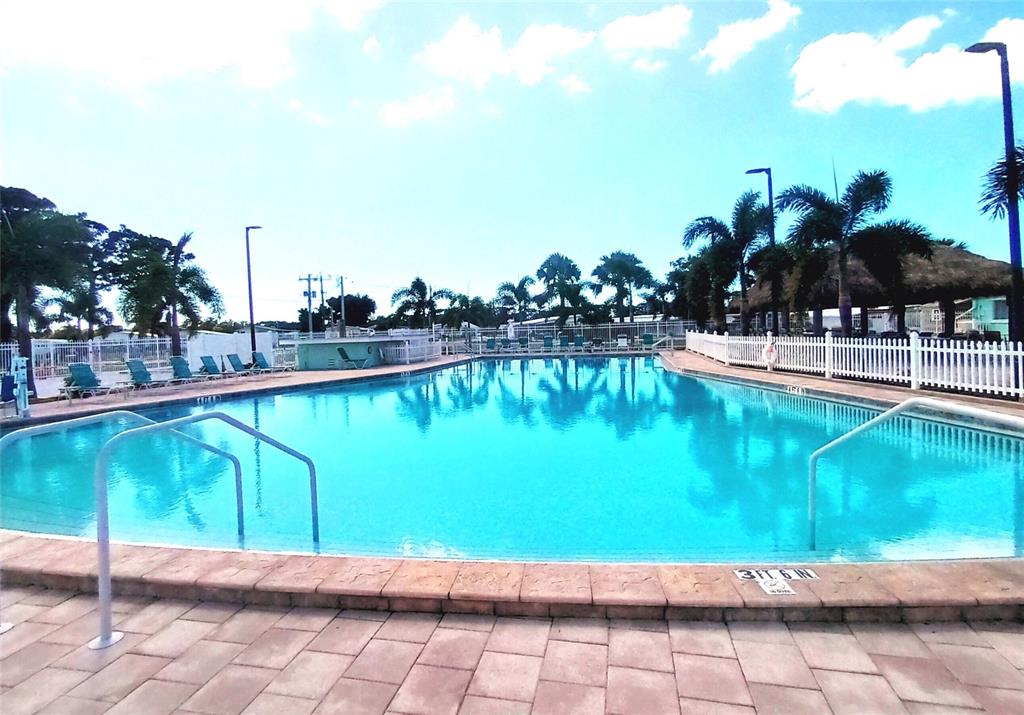 A large outdoor swimming pool is surrounded by a stone patio and a white fence — 4913 OAKLAND HILLS AVENUE, SARASOTA, FL