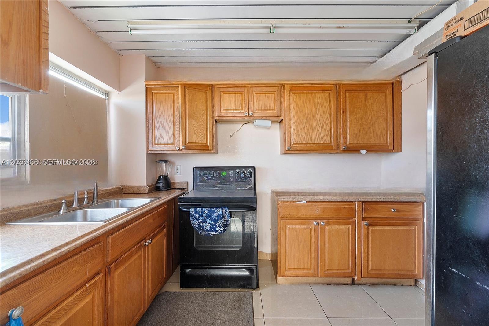 A kitchen features wood cabinets, laminate countertops, a black stove, and a double sink — 2301 NW 41st Ave # 302, Lauderhill FL 33313, LAUDERHILL, FL