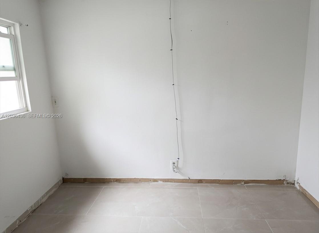 An empty room features white walls, light-colored floor tiles, and an exposed electrical cord — 2301 NW 41st Ave # 302, Lauderhill FL 33313, LAUDERHILL, FL