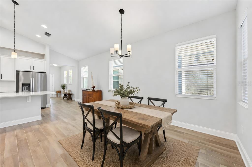 A dining area features a wooden table, black chairs, a chandelier, and light wood flooring — 606 DOGFISH LANE, DEBARY, FL