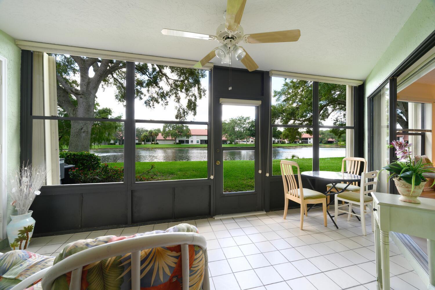 A sunroom with white tile floors, a ceiling fan, and a view of a lake — 6030 SE Martinique Drive # 102, Stuart FL 34997, STUART, FL