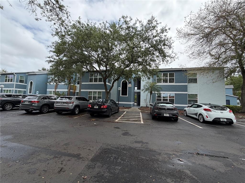 A two-story apartment building with a parking lot in front and several parked cars — 5713 GATLIN AVENUE UNIT 227, ORLANDO, FL