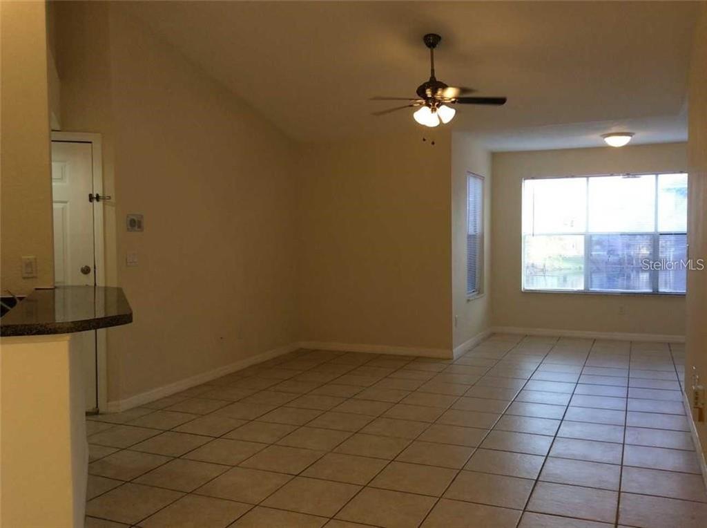An interior view of a room with light-colored tile flooring and a ceiling fan — 5713 GATLIN AVENUE UNIT 227, ORLANDO, FL