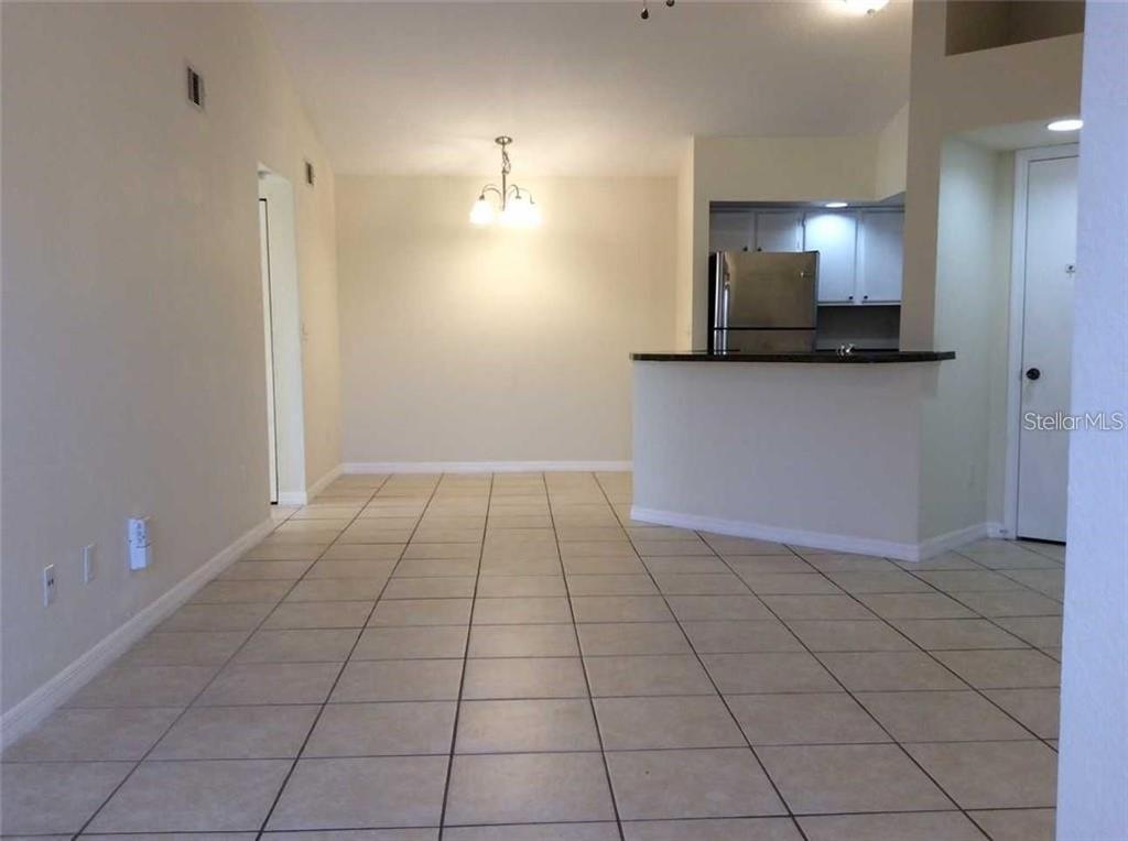 An open-concept dining area features tile flooring, a chandelier, and a kitchen with a breakfast bar — 5713 GATLIN AVENUE UNIT 227, ORLANDO, FL