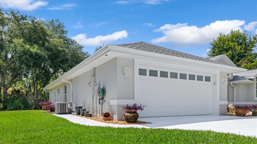 A light gray house exterior features a white garage door, landscaping, and a green lawn — 48 BARRING PLACE, PALM COAST, FL