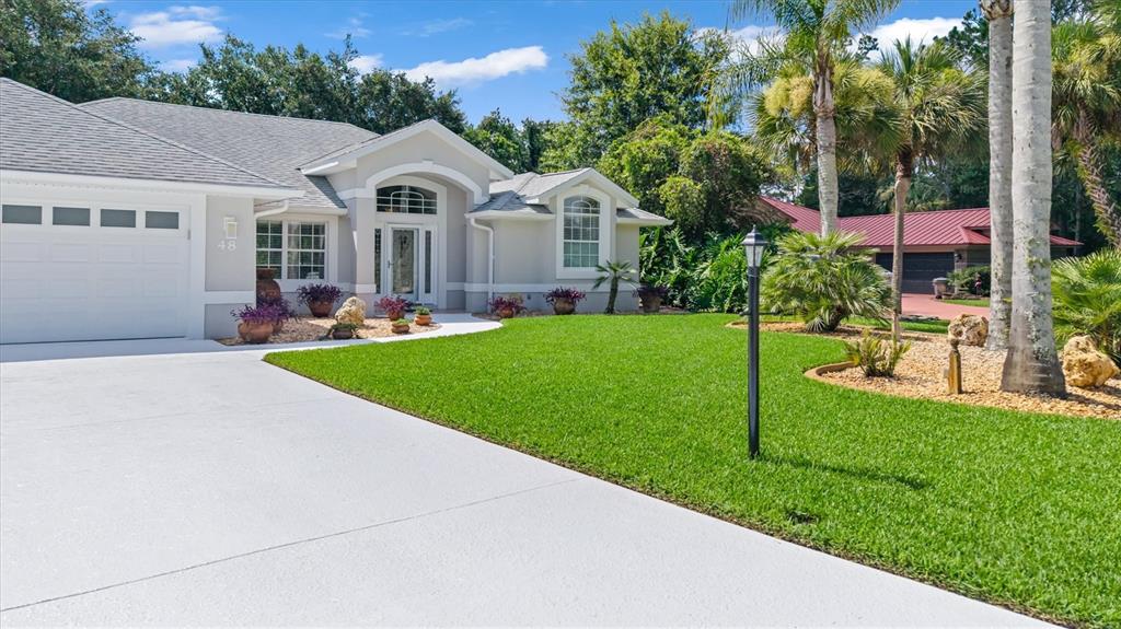 A single-story house with a white garage, arched entryway, and a green lawn — 48 BARRING PLACE, PALM COAST, FL