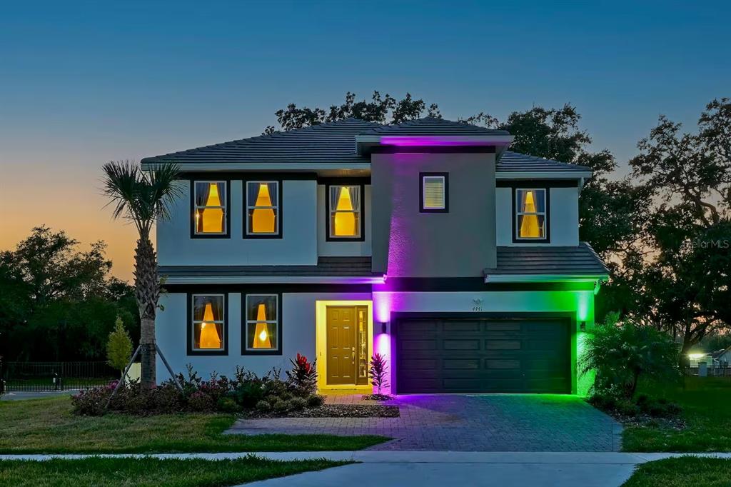 A two-story suburban house with exterior accent lighting at dusk — 4441 GANESHA LOOP, KISSIMMEE, FL