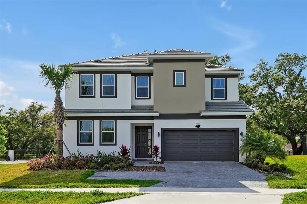 A two-story house with a white and tan exterior, a dark garage, and a palm tree — 4441 GANESHA LOOP, KISSIMMEE, FL