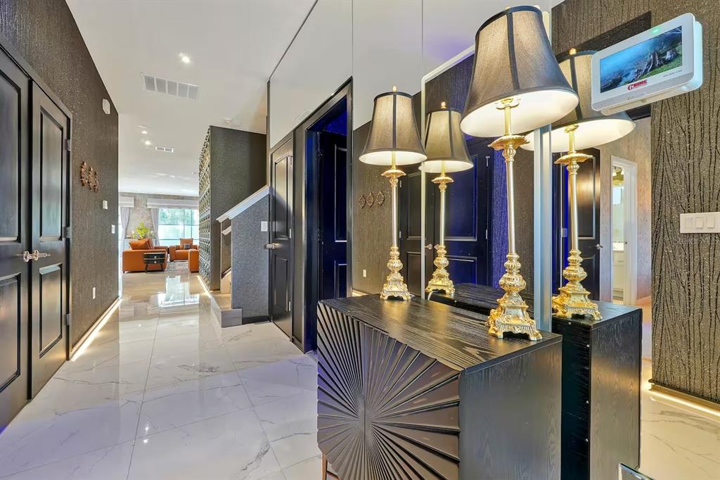 A hallway with white tile floors, black doors, and a mirrored console table with lamps — 4441 GANESHA LOOP, KISSIMMEE, FL