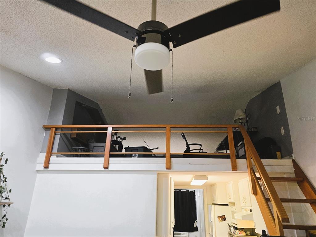 A room with a ceiling fan features a wooden loft area accessed by a staircase — 20857 HAULOVER COVE UNIT B14, LUTZ, FL