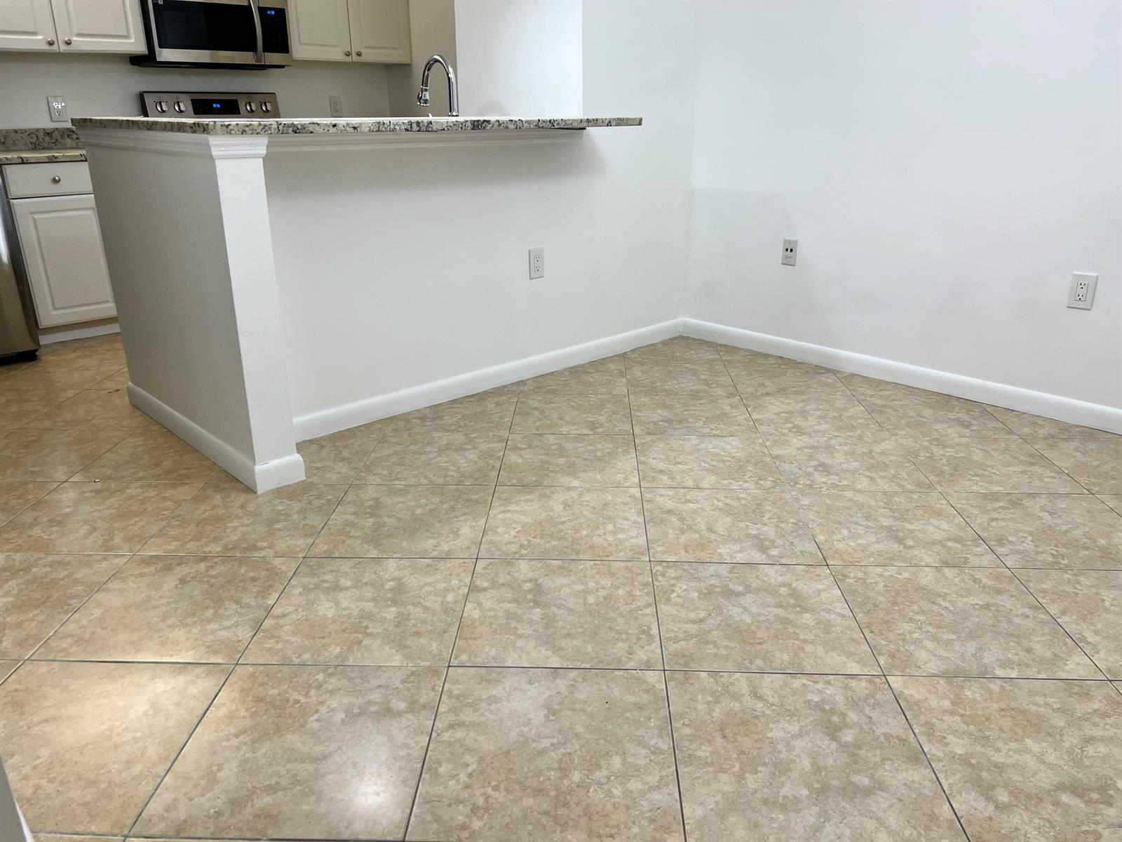 A kitchen with a granite countertop breakfast bar, white cabinetry, and beige tile flooring — 3114 31st Way, West Palm Beach FL 33407, WEST PALM BEACH, FL