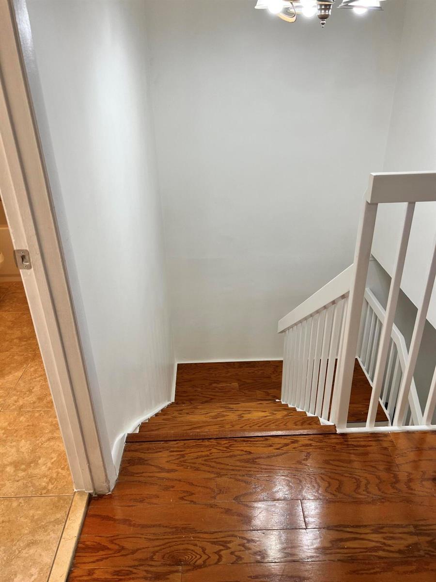 A view looking down a wooden staircase with white railings toward a landing — 3114 31st Way, West Palm Beach FL 33407, WEST PALM BEACH, FL