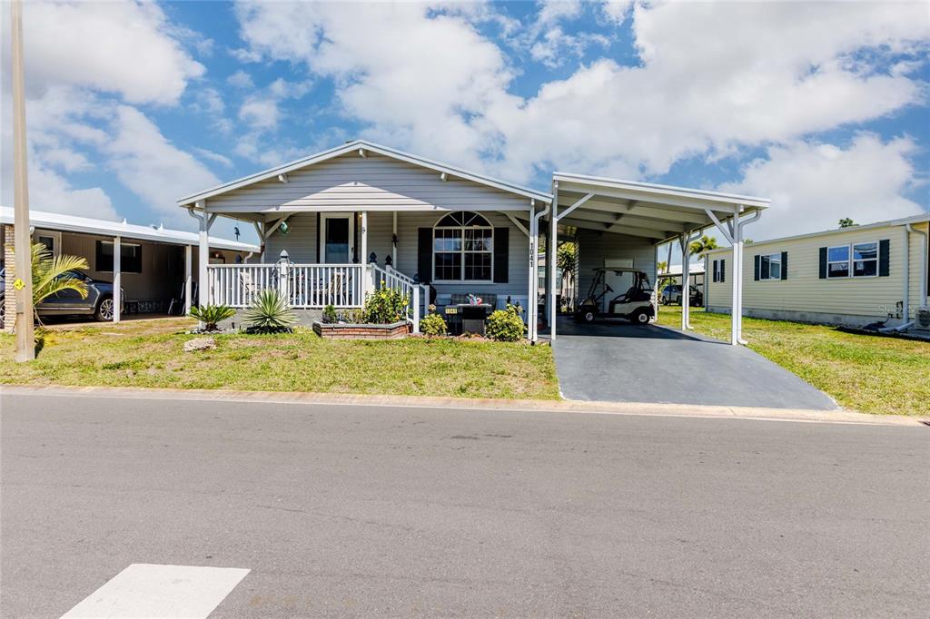 A light gray manufactured home with a front porch, carport, and golf cart — 2100 KINGS HIGHWAY #1041, PUNTA GORDA, FL