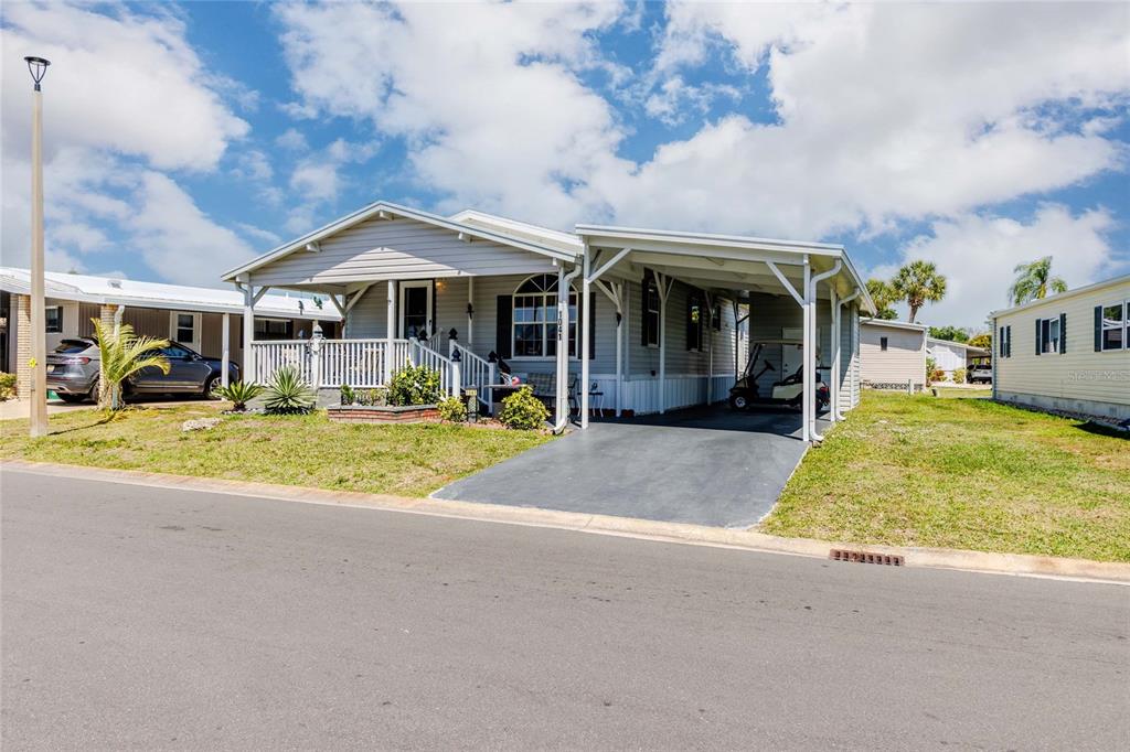 A light gray manufactured home features a front porch, a carport, and a paved driveway — 2100 KINGS HIGHWAY #1041, PUNTA GORDA, FL