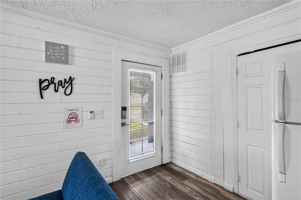 A room with white shiplap walls, a glass-paneled door, and a white refrigerator — 745 HILLVIEW DRIVE, ALTAMONTE SPRINGS, FL