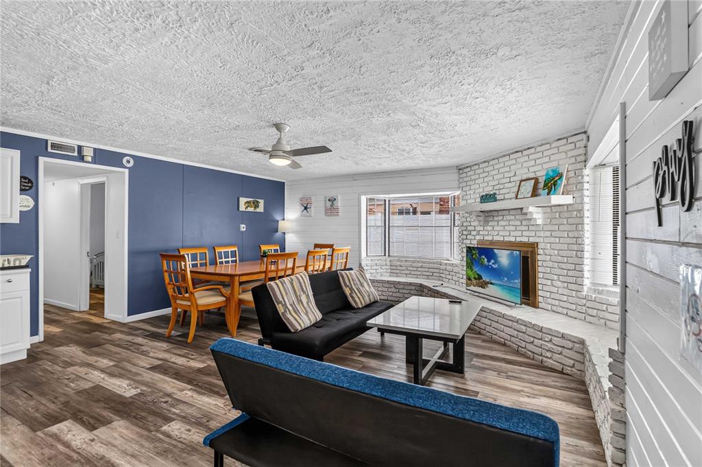 A living and dining area features wood-look flooring, a blue accent wall, and a brick fireplace — 745 HILLVIEW DRIVE, ALTAMONTE SPRINGS, FL