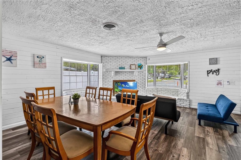 A dining area and living space with white shiplap walls, wood flooring, and a brick fireplace — 745 HILLVIEW DRIVE, ALTAMONTE SPRINGS, FL