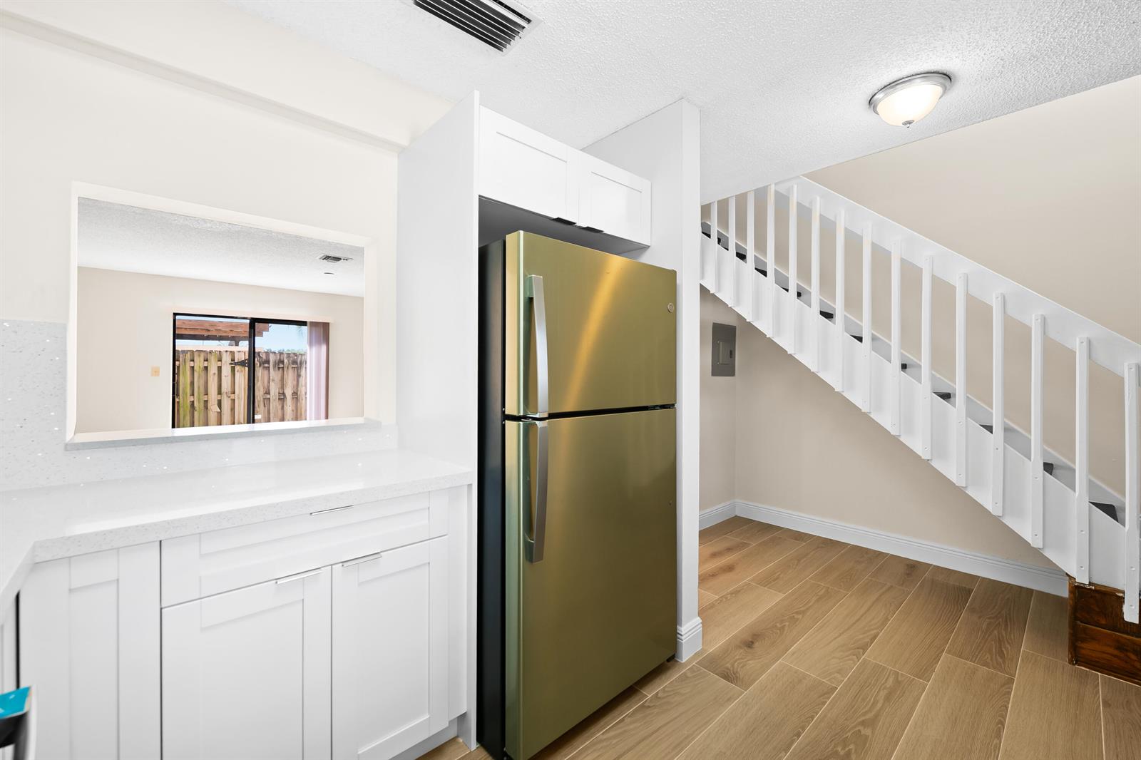 A kitchen area features white cabinets, a gold refrigerator, and stairs leading to an upper level — 3281 E Golf Boulevard # 12, Pompano Beach FL 33064, POMPANO BEACH, FL