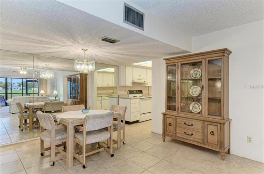 A dining area with a wooden hutch, tiled floors, and a view into the kitchen — 6120 43RD STREET W UNIT 102B, BRADENTON, FL