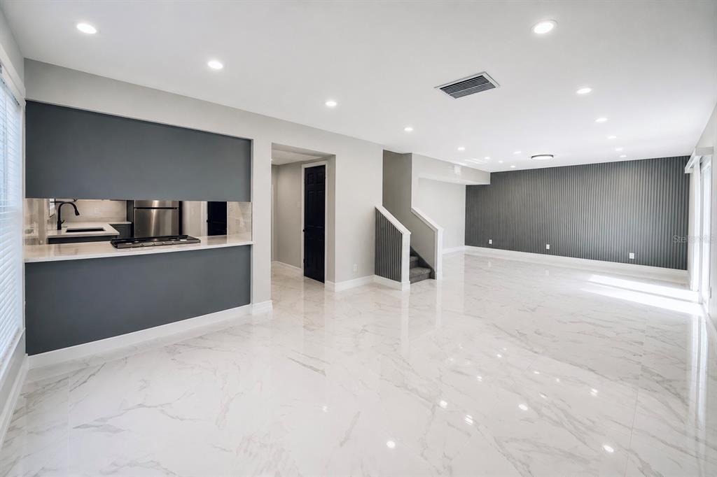 A bright, open-concept living area with white marble floors, a kitchen pass-through, and gray walls — 12414 TOUCHTON DRIVE UNIT 98, TAMPA, FL