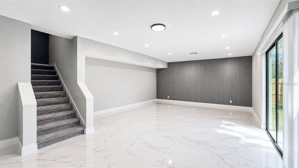 A room with white marble-look tile flooring, a carpeted staircase, and a gray slatted accent wall — 12414 TOUCHTON DRIVE UNIT 98, TAMPA, FL